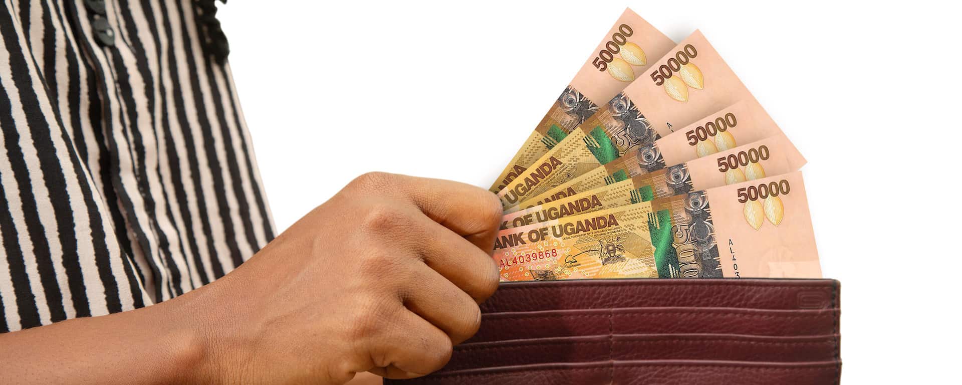 fair Female Hand Holding brown Purse With Ugandan shilling notes, hand removing money out of purse isolated on white. removing money from wallet